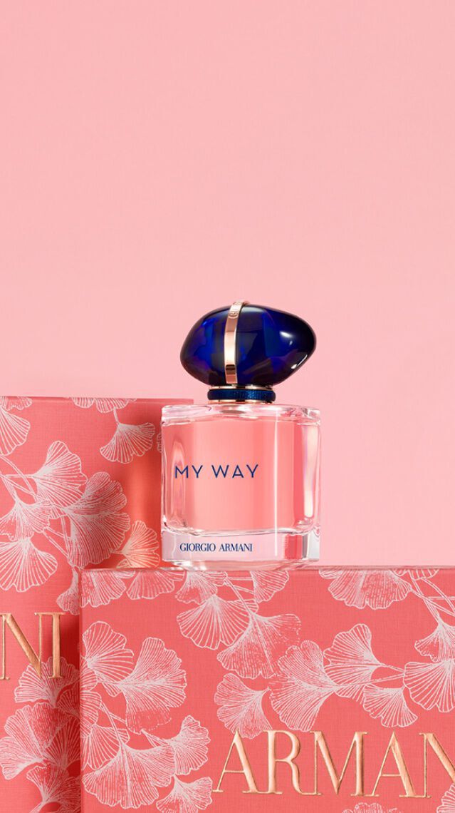 Un flacon de parfum "My Way" d'Armani sur des boites florales, le tout sur un fond rose.