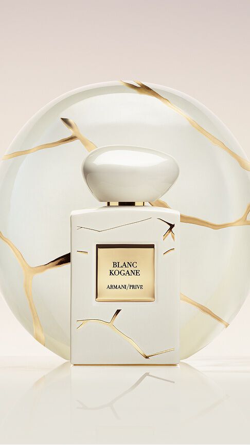 Armani/Prive Blanc Kogane: a pure white bottle with gold marbling, set before a Kintsugi porcelain plate, symbolizing serene femininity and the solar radiance of white jasmine and lily flowers.