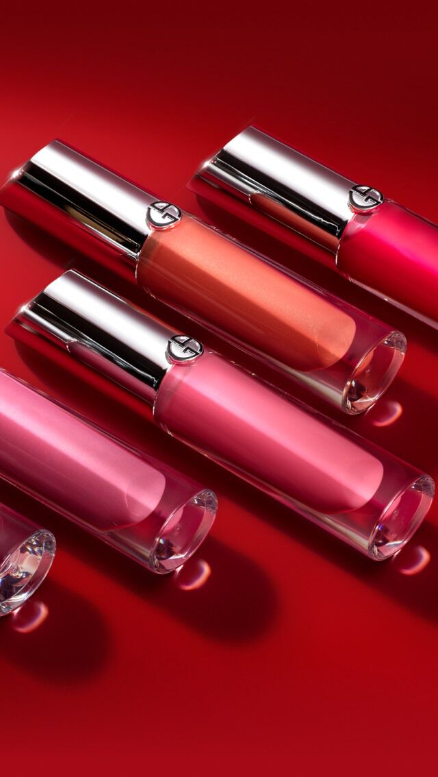 Cinq flacons de vernis a levres aux couleurs variees (rouge, rose, corail) sur un fond rouge.