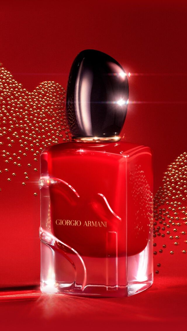 Flacon de parfum elegant sur fond rouge, avec des effets scintillants en arriere-plan.
