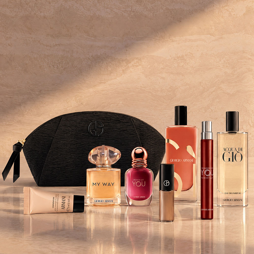 Une pochette noire Armani Beauty accompagnee de parfums, de maquillage et de soins sur un fond beige.
