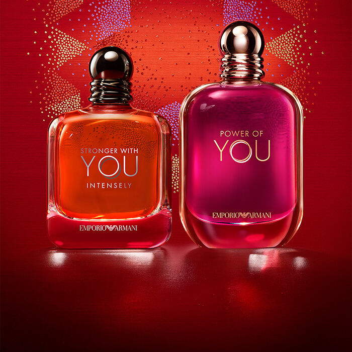Deux parfums Emporio Armani, Stronger With You Intensely et Power of You, sur un fond festif rouge.​