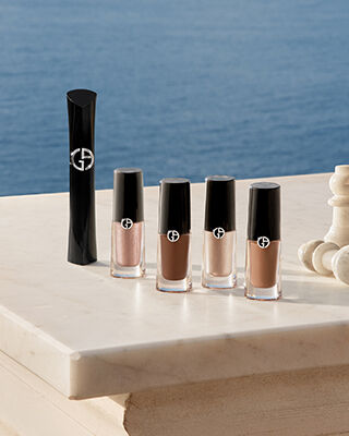Eye make-up products arranged on a terrace table, with the sea behind.
