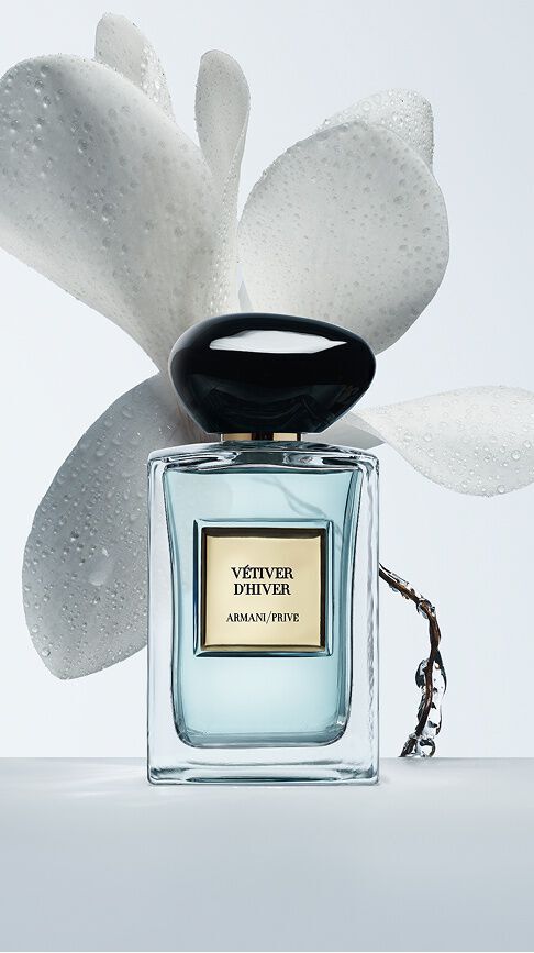 Armani/Prive Vetiver d'Hiver : un flacon revelant un nectar bleu clair, encadre par des petales blancs delicats perles de rosee, evoquant la fraicheur vive et lumineuse de l'hiver.
