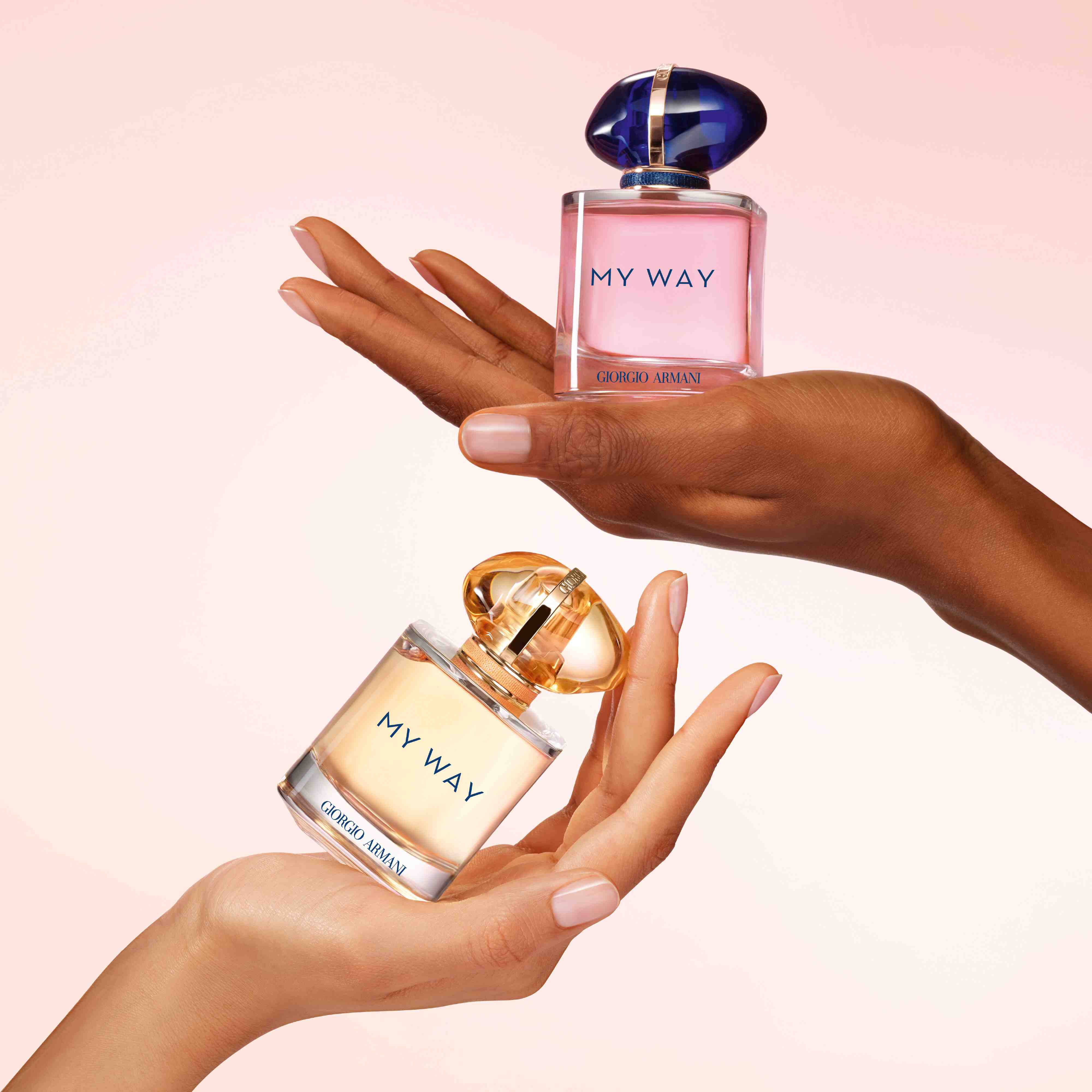 Deux mains de carnations differentes tenant chacune un flacon du parfum My Way de Giorgio Armani.