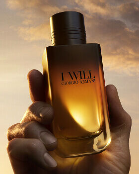 Giorgio Armani I WILL Eau de Parfum bottle held in hand. A refillable black-to-gold gradient design.