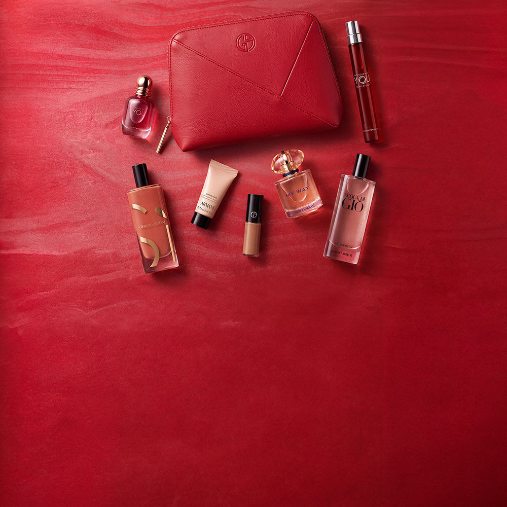 Trois produits Armani Beauty — un produit pour les levres, la fragrance Power of You et le fond de teint Luminous Silk — presentes sur un fond rouge texture.