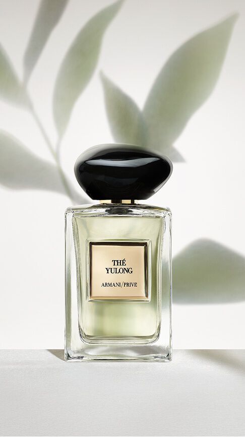 Armani/Prive The Yulong : un flacon revelant une essence vert pale, sur un fond minimaliste d'ombres de feuilles, incarnant l'equilibre serein entre the fume et the vert.