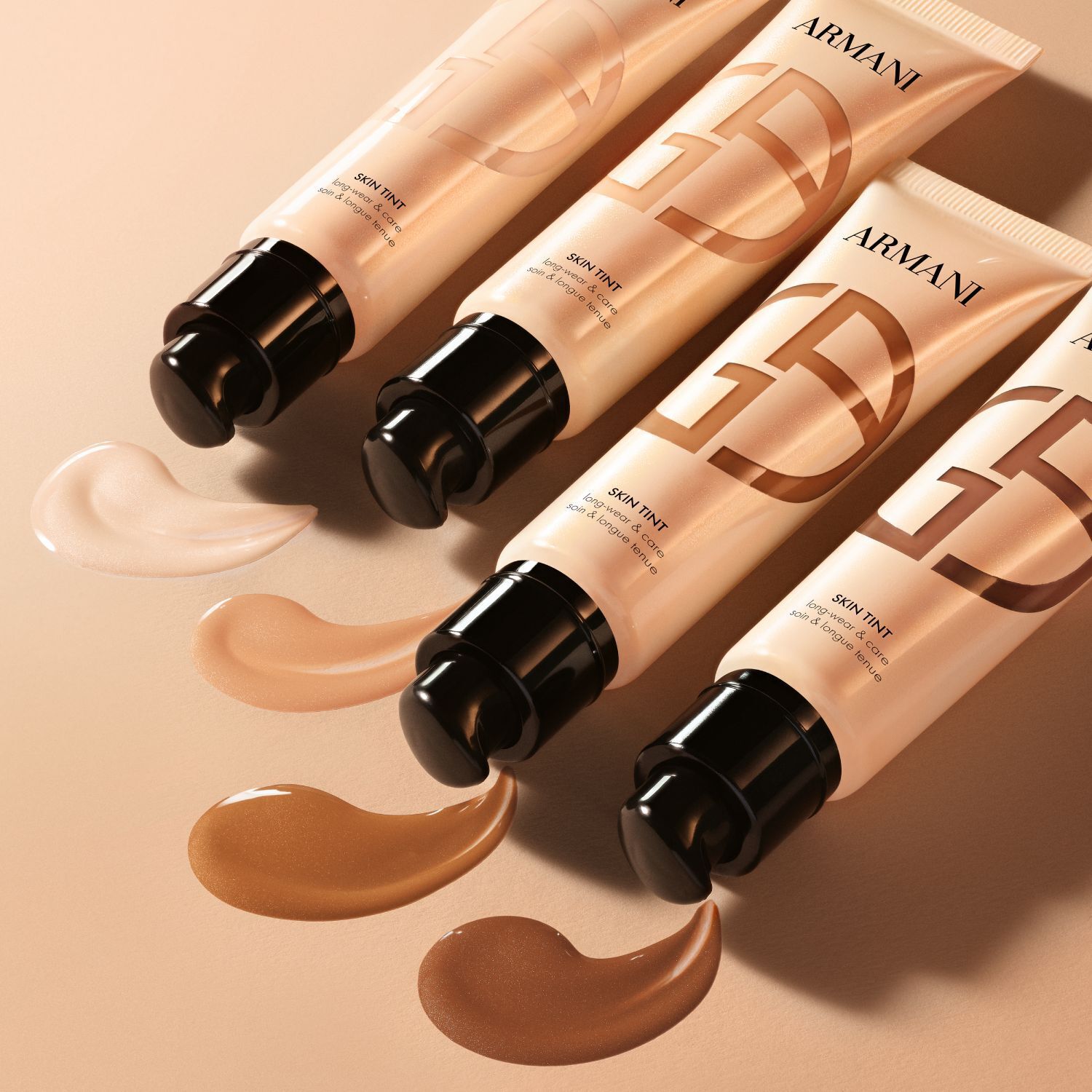 Quatre tubes d Armani Skin Tint avec des echantillons appliques montrant une gamme de nuances.