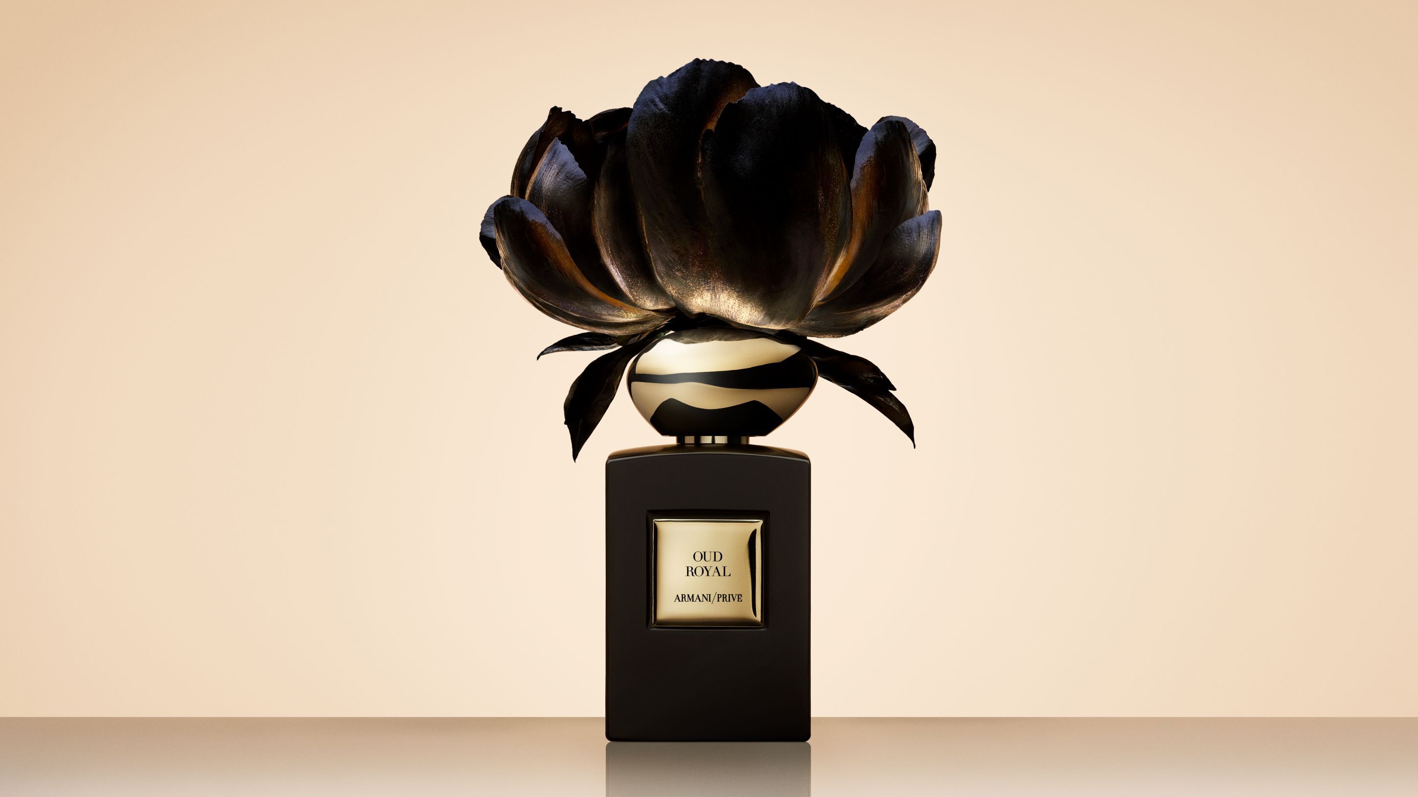 Flacon de parfum Armani/Prive Oud Royal surmonte d'une grande fleur noire artistique.