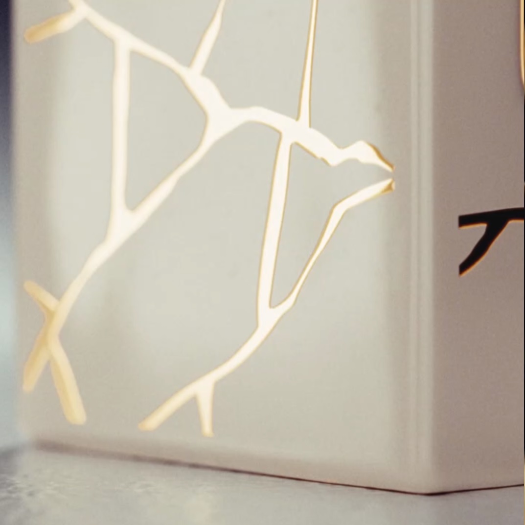 Un objet décoratif en céramique blanche avec des motifs de fissures dorées illuminées.
