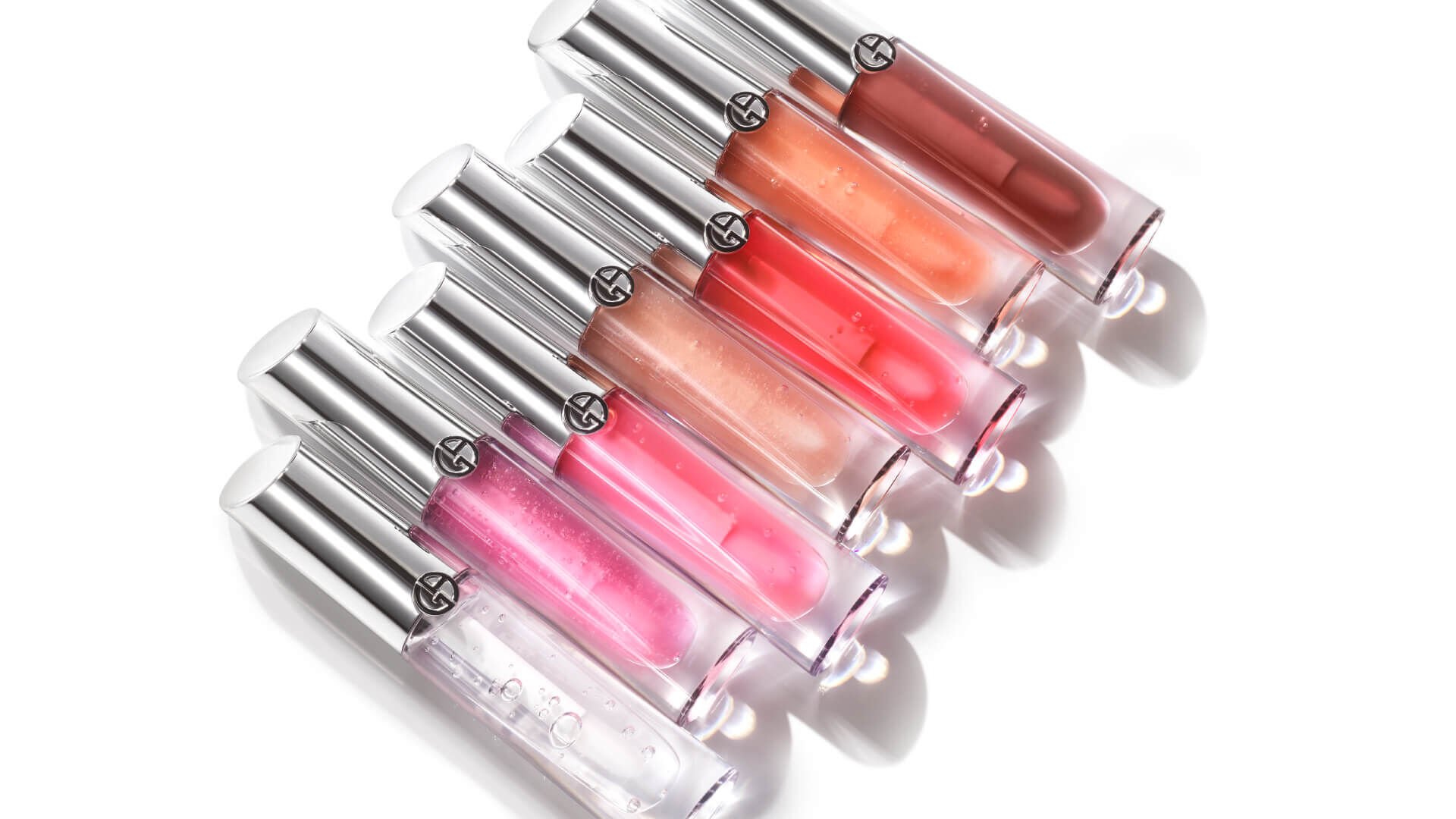 Gamme de gloss à lèvres Armani, présentée en sept teintes, avec des tubes transparents et des bouchons argentés.
