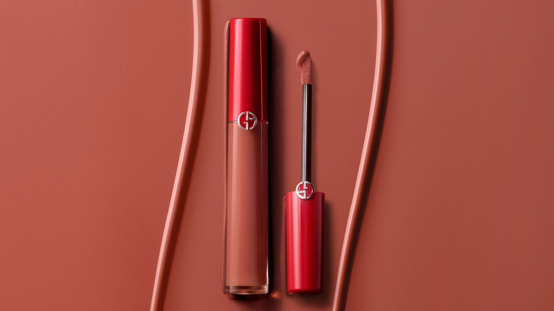 Rouge à lèvres liquide Giorgio Armani avec applicateur sur fond terracotta texturé.