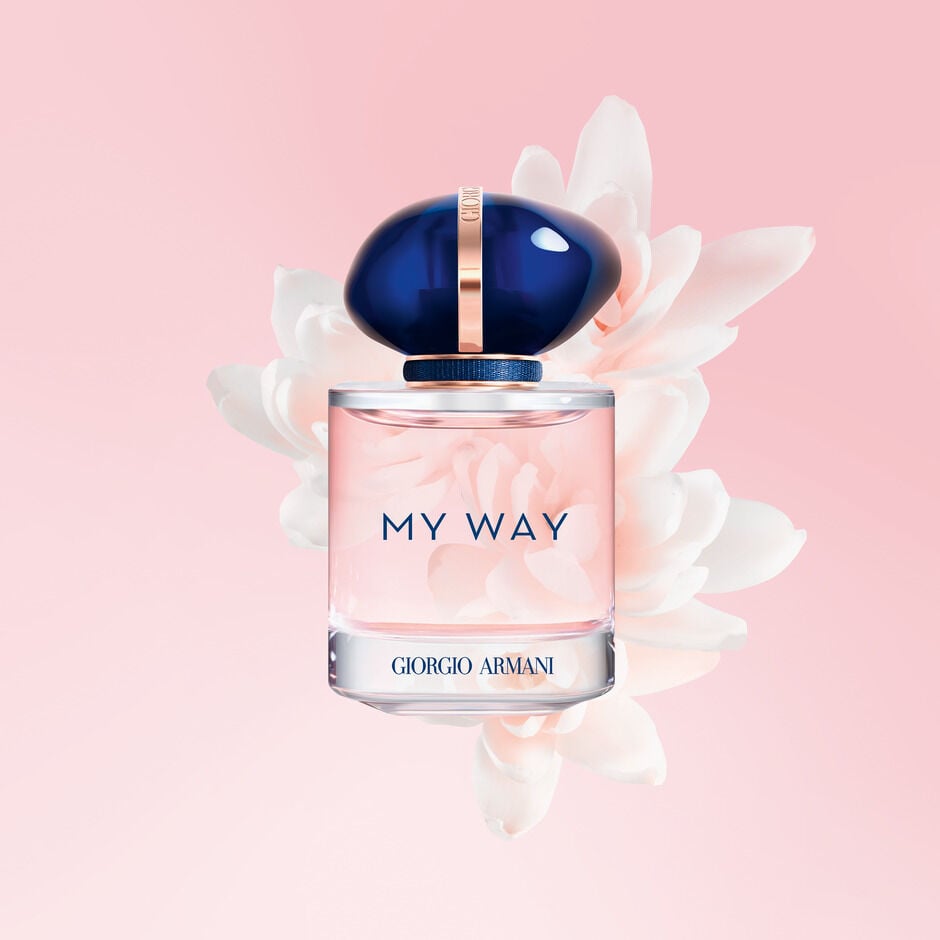 Flacon de parfum 'My Way' de Giorgio Armani, entouré de fleurs blanches sur fond rose. Élégance et sophistication.