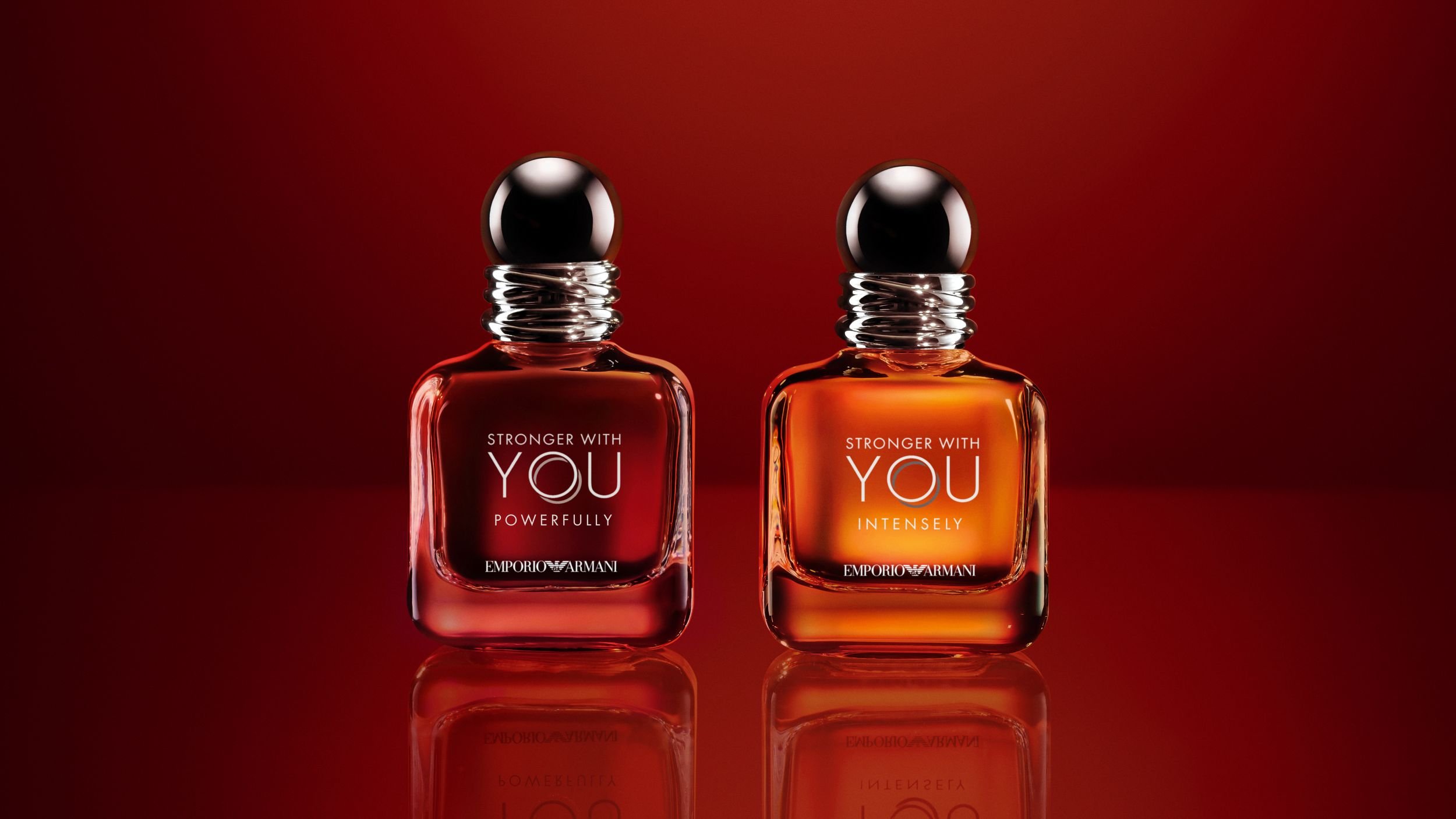 Deux flacons de parfum Emporio Armani « Stronger With You » sur un fond rouge réfléchissant.